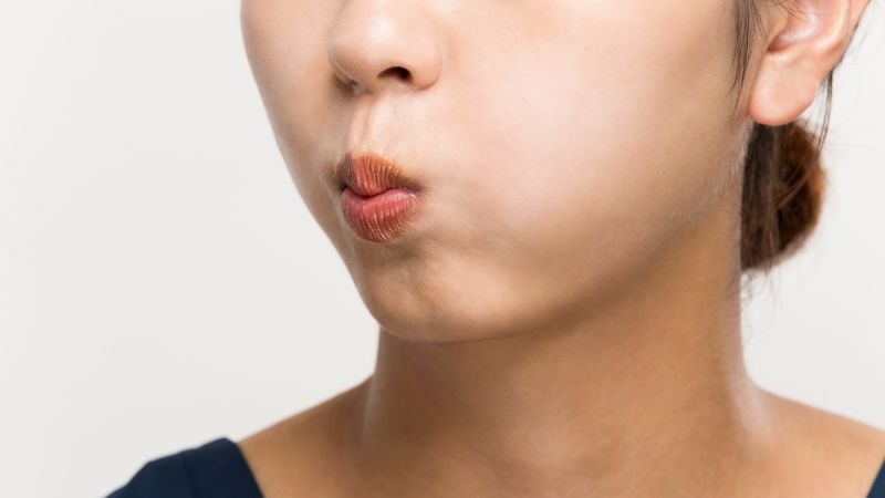 片頬を膨らませる女性