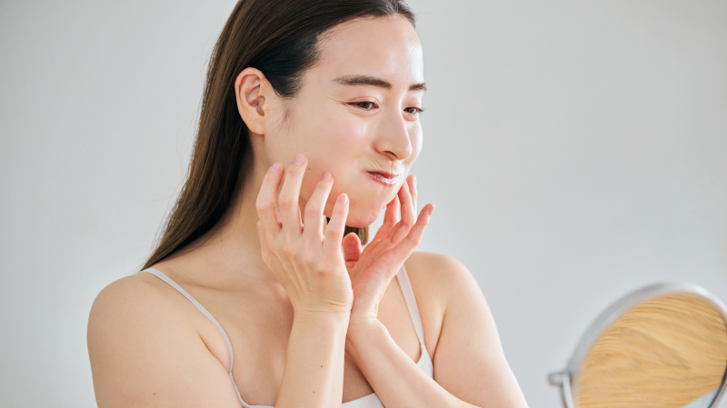 鏡を見ながら頬を膨らませる表情筋トレーニングをする女性