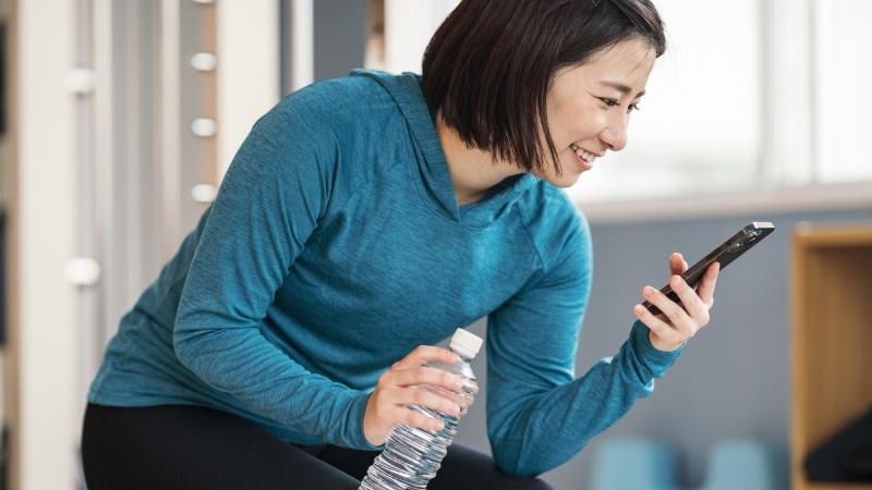 トレーニングウェアを着てスマホを見る女性