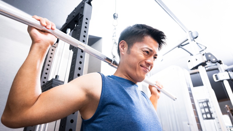 ビハインドネックラットプルダウンをする苦しそうな表情の男性