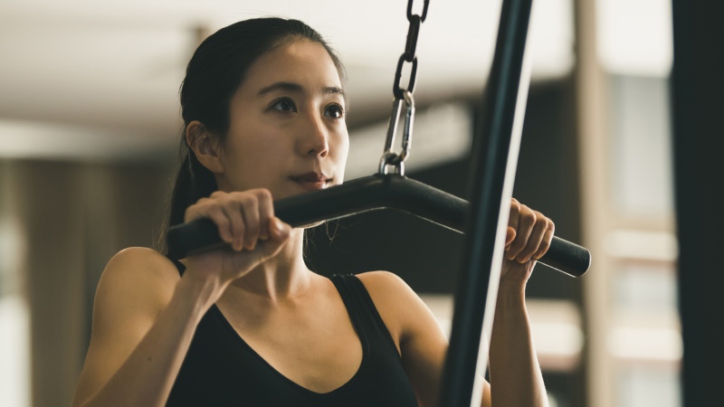 ナローグリップでラットプルダウンをする女性