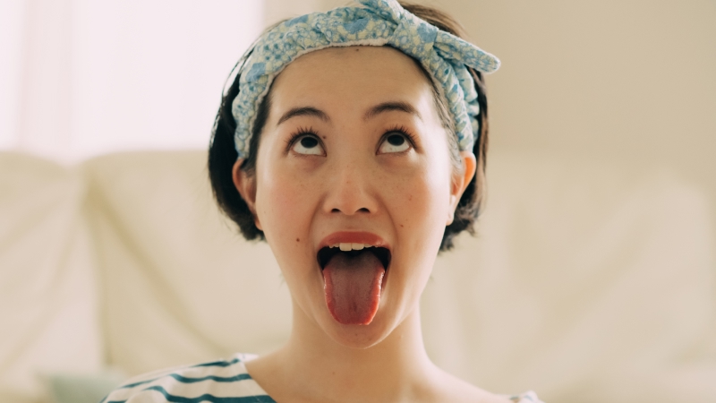 口を大きく開けて舌を下方向に思い切り出して上を見る女性